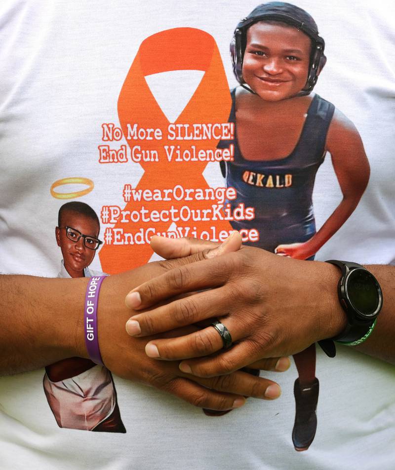 Brandon Elion, stepfather of Ezra Hill Jr., wears a gift of hope bracelet and a stop gun violence shirt with Ezra’s photo on it as he and Ezra’s mom Andrea Harden talk about him Monday, May 12, 2025, at Tyler Elementary School. Hill was murdered in 2019 in Harvey, and the Fifth Annual Ezra Hill Jr. Memorial Rock Painting event will be held on June 7 at the school in DeKalb.