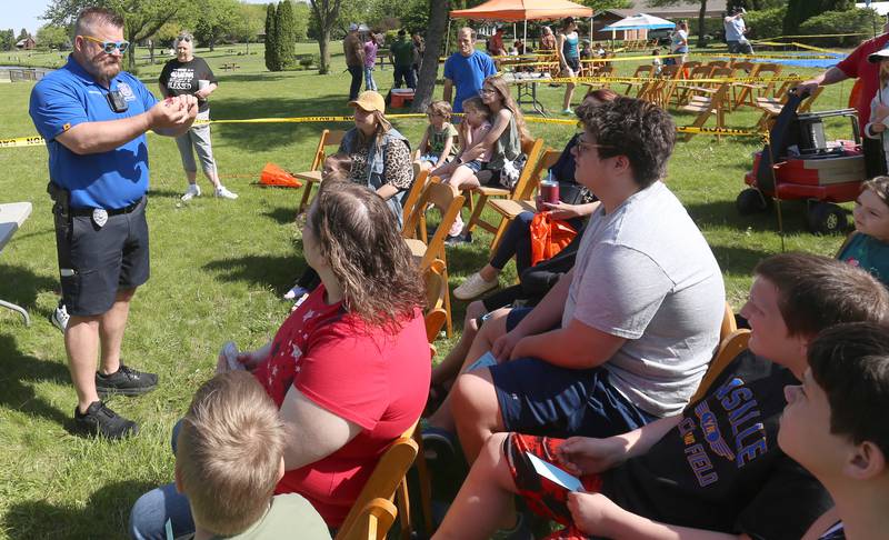 Peru Police officer Brian Zebron, teaches kids different tackle hooks and fishing lures along with other items found in a tackle box during the 25th annual Kids Fishing Expo on Saturday, May 10, 2025 at Baker Lake in Peru.