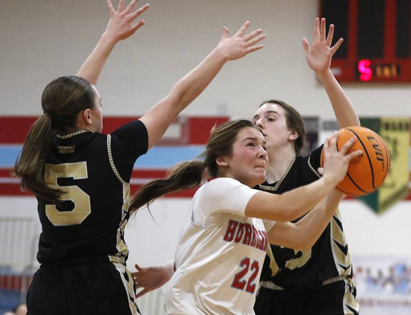 Marian Central's Jenna Remke splits the defense of Rockford Christian's Shea Ludwig (left) and Madigan Rhode (right) during a nononference basketball game on Monday, Feb. 10, 2025, at Marian Central High School  in Woodstock.