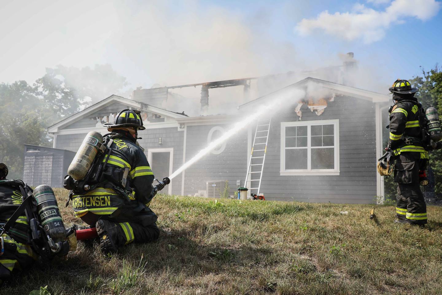 Firefighters work together to extinguish a Woodstock house fire on Friday, July 21, 2023.