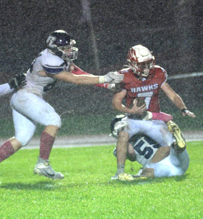 Two Rockford Lutheran defenders tackle Logan Weems in the rain at Landers-Loomis Field on Friday, Oct. 13, 2023.