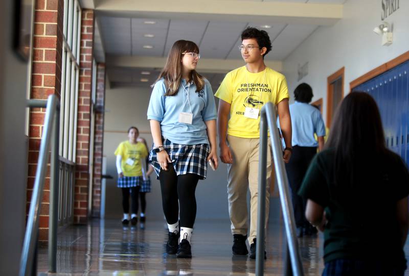Nazareth Academy student Thomas Delgado (right) helps incoming freshman Brianna Forssander navigate the hallways of the La Grange Park school on Friday, Aug. 16, 2024 as part of Freshman Orientation.