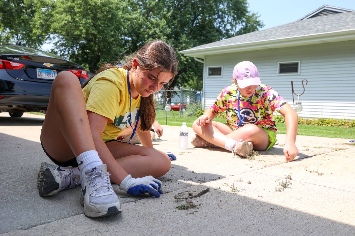 Amelia Nugent, 13, left, of Manteno, pulls weeds alongside fellow youth volunteer Ella Absher, 13 of Bourbonnais, at a project site in Bourbonnais on July 22, 2025, during the 9th Camp MOSH, a week-long volunteer service camp from Maternity BVM parish.