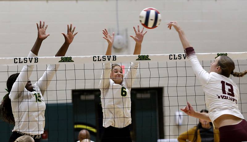 Prairie Ridge's Abigail Smith (right) tries to hit the ball through the block of Crystal Lake South's Sahara Okiria (left) and Bobbi Wire (center) during the IHSA Class 3A Crystal Lake South Sectional final volleyball match on Thursday, Nov. 7, 2024, at Crystal Lake South High School.