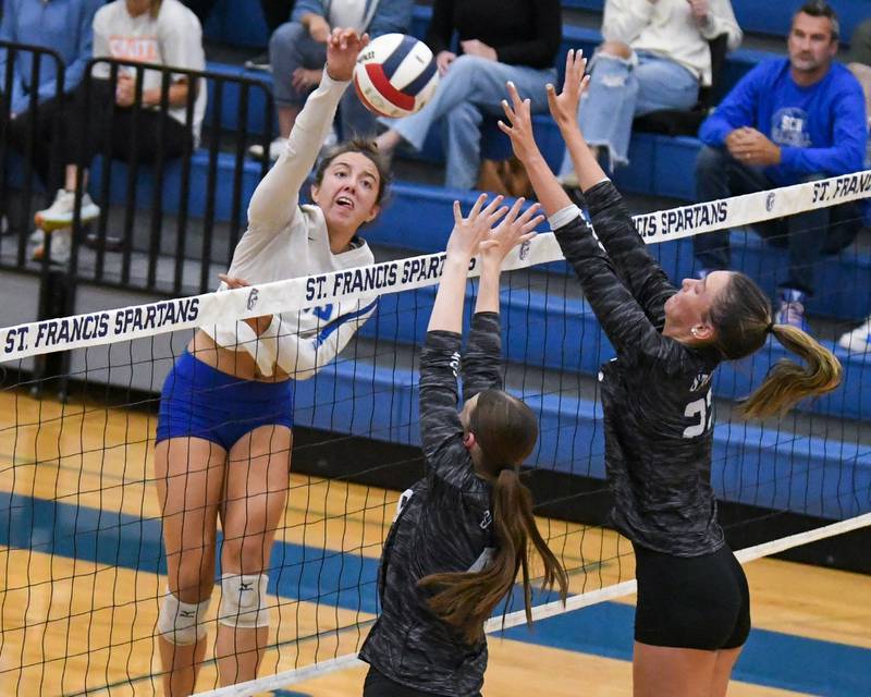 St. Charles North’s Haley Burgdorf, left, spikes the ball past St. Francis defenders Grace Grover, center, and Addy Horner, right, during the game on Wednesday Oct. 2, 2024, held at St. Francis High school in Wheaton.