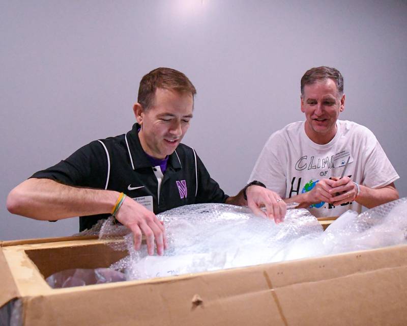 Mike Heinz, right, and Jeff Grant unwrap approximately 1,270 years old ice from Greenland at Downers Grove North High School during The Climate of Hope Conference 2024, held on Friday March 1, 2024.