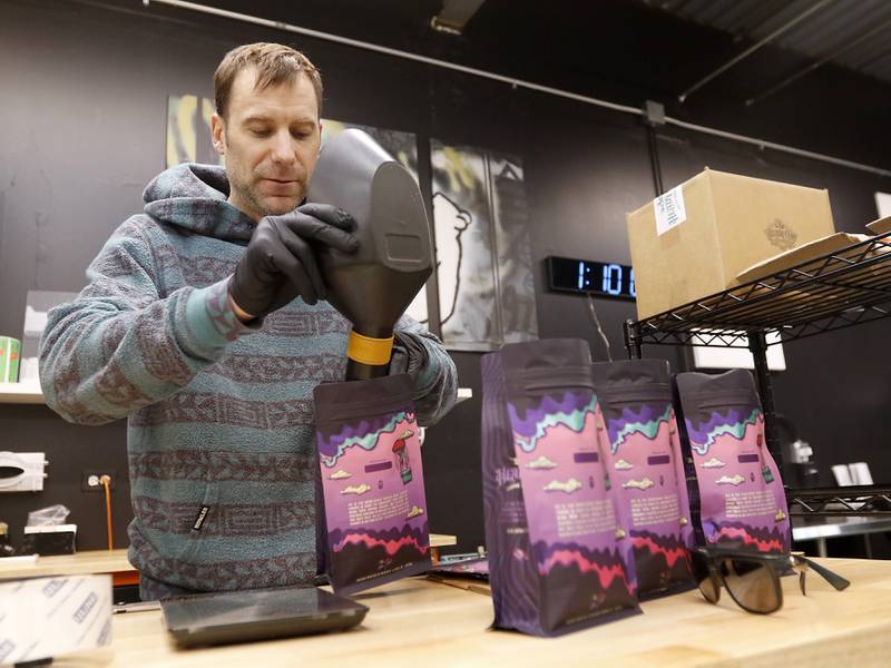 Michael Kivland, a co-owner of Heady Cup Coffee Roasters, weighs beans on Friday, Feb. 14, 2025, as he packages coffee at the business in McHenry.
