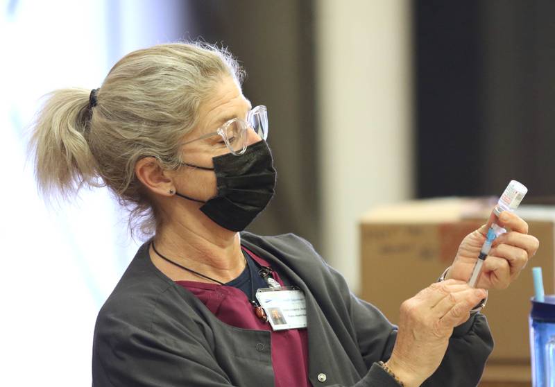 Kerri Donahue, DeKalb County Health Department public health nurse, fills a syringe with COVID-19 vaccine during the clinic Thursday at Sandwich High School