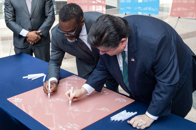 Gov. JB Pritzker (right) and Chicago Mayor Brandon Johnson (left) together sign a panel that once hung on the James R. Thompson Center in Chicago. After being sold by the state, the building is being renovated to make space for its next occupant, Google.