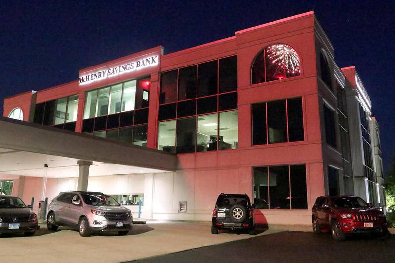 A file photo of McHenry Savings Bank, lit in a red hue by fireworks, in McHenry.