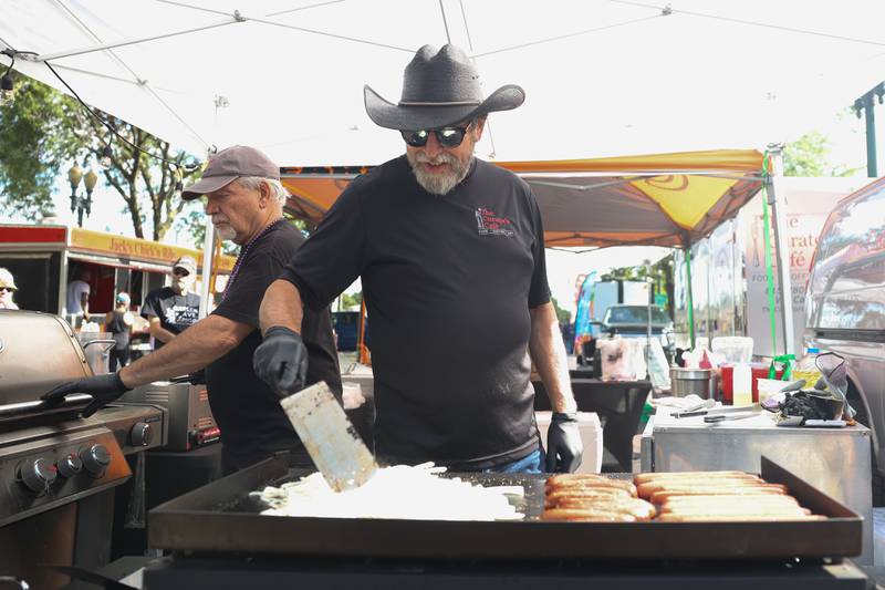 Jim Dodaro, left, makes an order while Tom Grotovsky works the grill at The Curator’s Cafe tent at the 6th Annual Joliet Blues Festival on Saturday, Aug. 10, 2024 at Bicentennial Park.