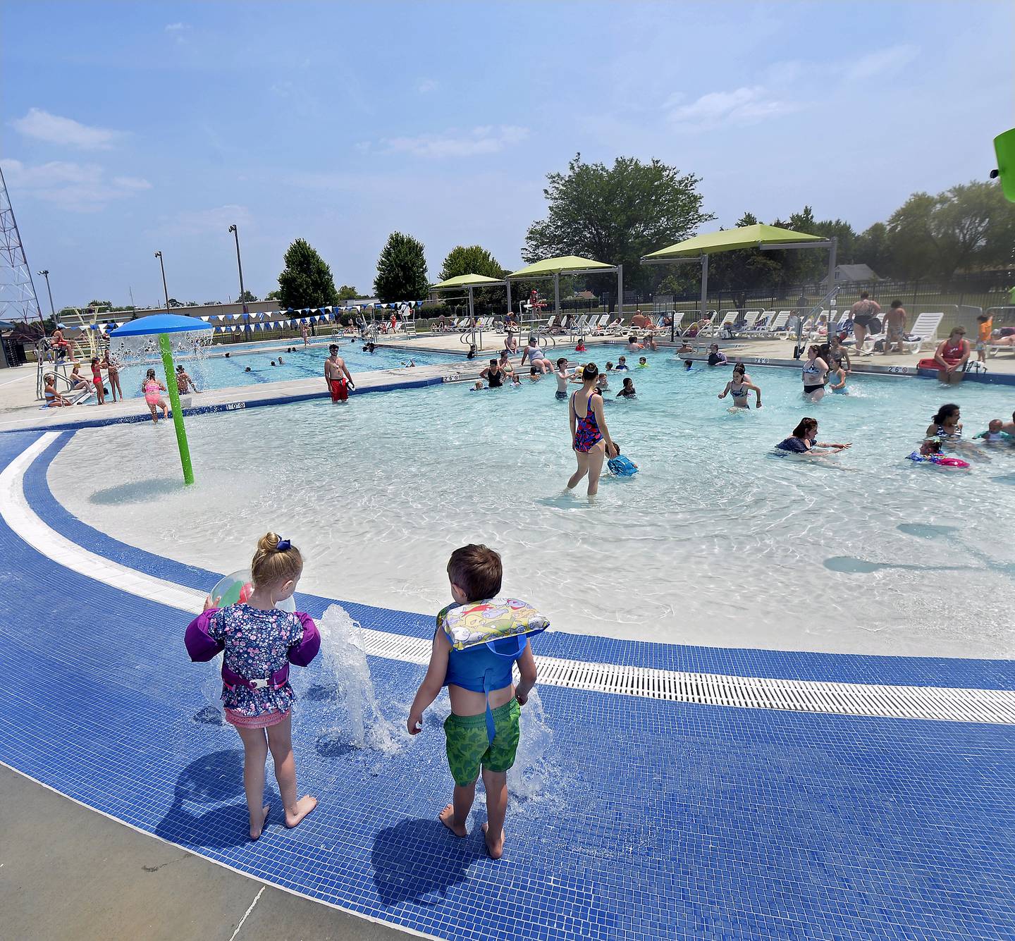 These two children enjoy fountains erupting before entering the zero-foot entry part of the pool Monday, June 19, 2023, during opening day of the new Riordan Pool In Ottawa.