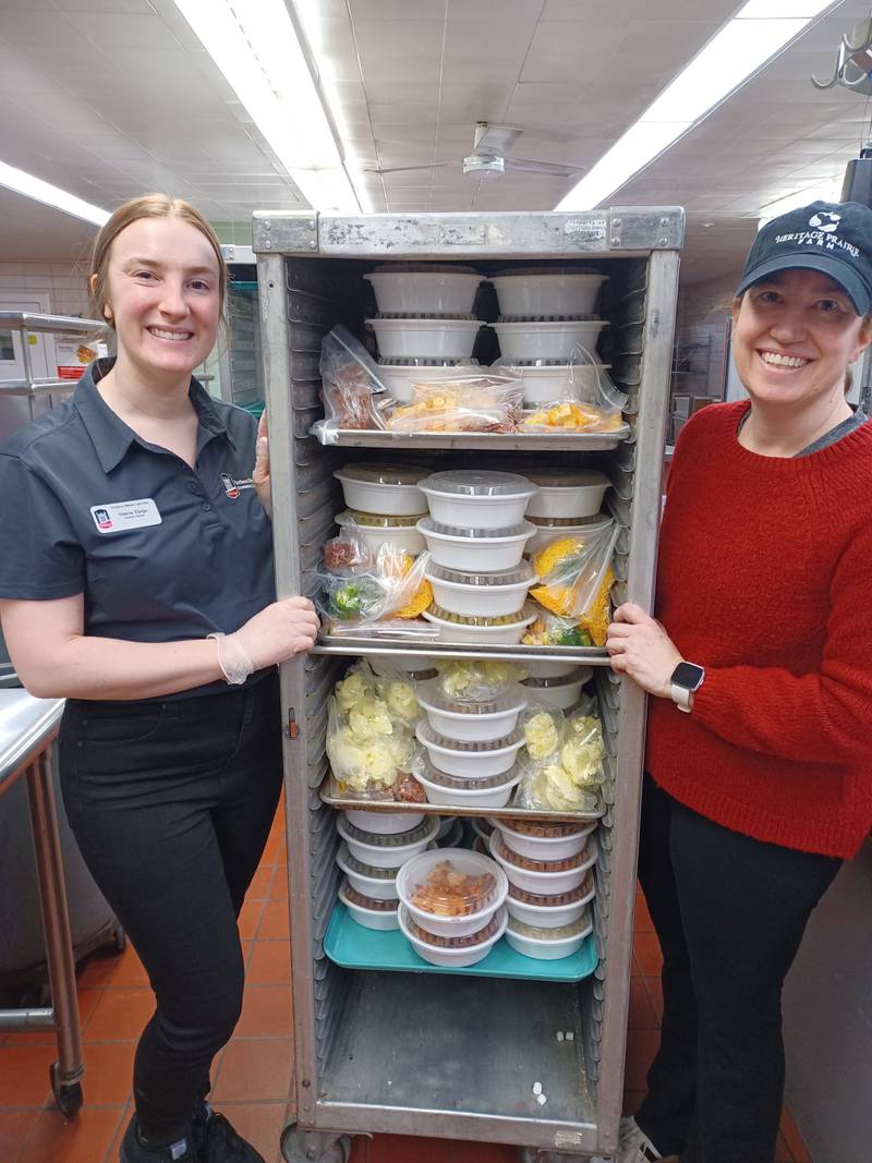 Nancy Prange, right, and dietetic intern Stacia Tietje stand next to food packaged as a part of the Huskie Harvest program. Photo provided by Northern Illinois University.