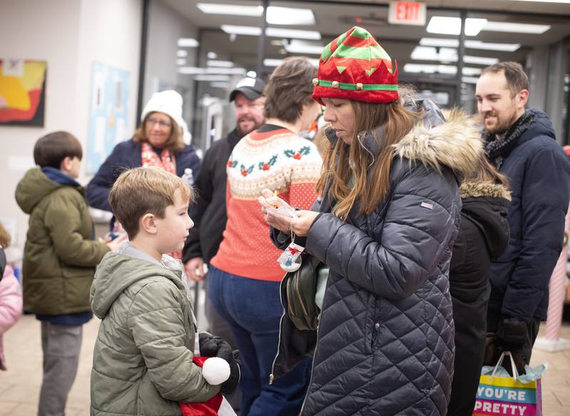 April Whittington, right, of Bradley, fills out a name card for her son Crosby, 8, left, for a chance to assist Kankakee Mayor Chris Curtis lay the holiday wreaths on the lion statues outside the Kankakee Library on Thursday, December 4, 2025.