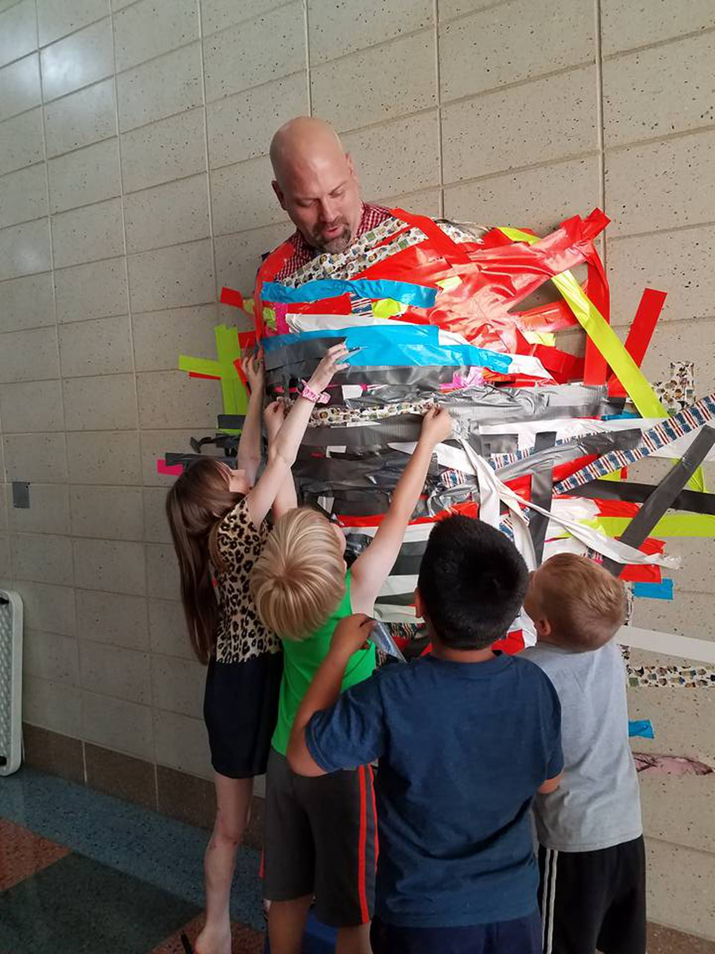 Principal Dave Raffel allows his students to tape him to the wall for charity.
