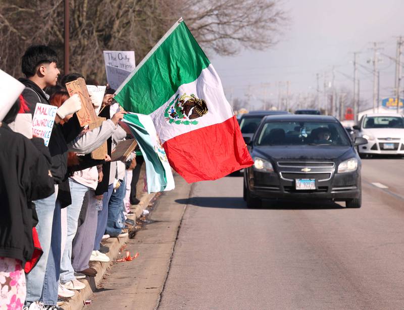 DeKalb High School students hold flags and signs during a protest Tuesday, Feb. 10, 2026, on Sycamore Road in front of Hopkins Park in DeKalb. The students walked out of school Tuesday to protest against ICE involved violence and arrests.