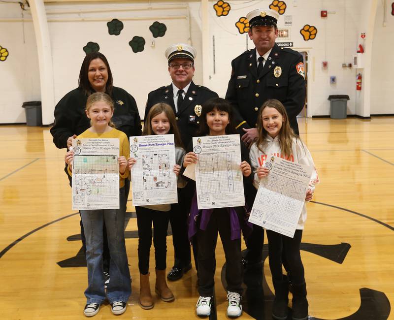 Putnam County Elementary students (from left) Octavia Walter, Giada Wright, Priscilla Serna and Krya King pose for a photo with their escape plans with principal Courtney Balestri, Hennepin Fire Department deputy chief Quentin Buffington, and lieutenant Tyler Smith on Tuesday, Nov. 21, 2023 at Putnam County Elementary School in Hennepin. Students at the school won the Escape Floor Plan contest held by the fire depatment. Students had to draw a floor plan or map of their home showing all doors and windows. Smoke alarms had to be marked in each plan. A family meeting place was also required to be marked on the drawings. Winners were awarded Amazon gift cards for prizes. The Hennepin Fire Department has been holding the contest for several years. The department stopped the event during Covid and continued it for the first time since the pandemic this year. The department picks the winning children up on a firetruck and busses them to school.