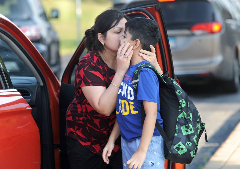 Second grader Vivan Kaur gets a kiss from his mom, Herpreet at the car dropoff on the first day of school at Grande Reserve Elementary in Yorkville on Thursday, Aug. 24, 2023.