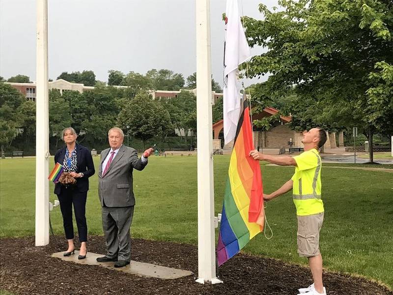 Batavia City Administrator Laura Newman, left, and Mayor Jeff Schielke watch as city worker Kevin Maloney raises a gay pride flag Monday evening at a plaza on the Batavia Riverwalk. It is the second year Batavia has raised such a flag to mark Pride Month, but the first time it has had a public ceremony to do so.