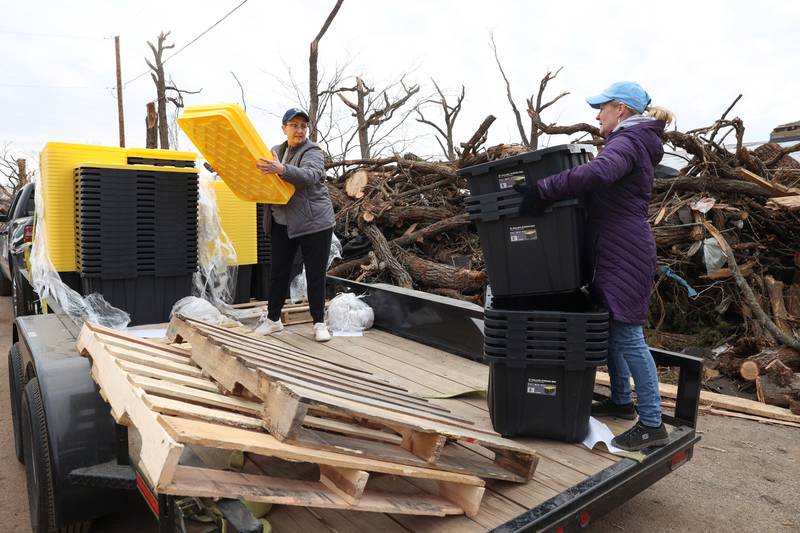 State Rep. Jackie Haas, left, and Lori Curtis help hand out plastic totes to residents in the Oakwoods subdivision in Aroma Township on March 14, 2026, following the March 10 tornado in Kankakee County. The group, including Kankakee Mayor Chris Curtis, Aroma Park Mayor Brian Stump, State Sen. Patrick Joyce and his wife Rita, and Kankakeean Elisabeth Dunbar, delivered the donated bins to affected areas in the county.