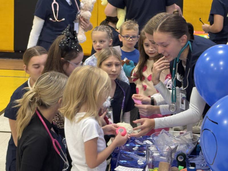 A Grundy Area Vocational Center health occupations student shows a Nettle Creek School student how to apply a bandage to her stuffed animal. Photo taken on Wednesday, Nov. 11, 2025.