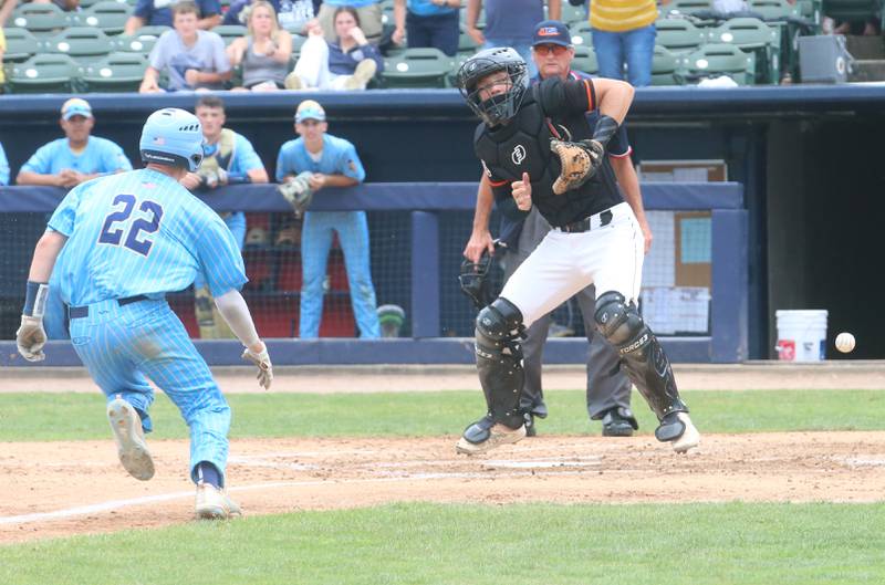 Marquette's Griffin Dobberstein scores the teams first run as the ball gets away from Altamont catcher Nathan Stuemke during the Class 1A State championship game on Saturday, June 1, 2024 at Dozer Park in Peoria.