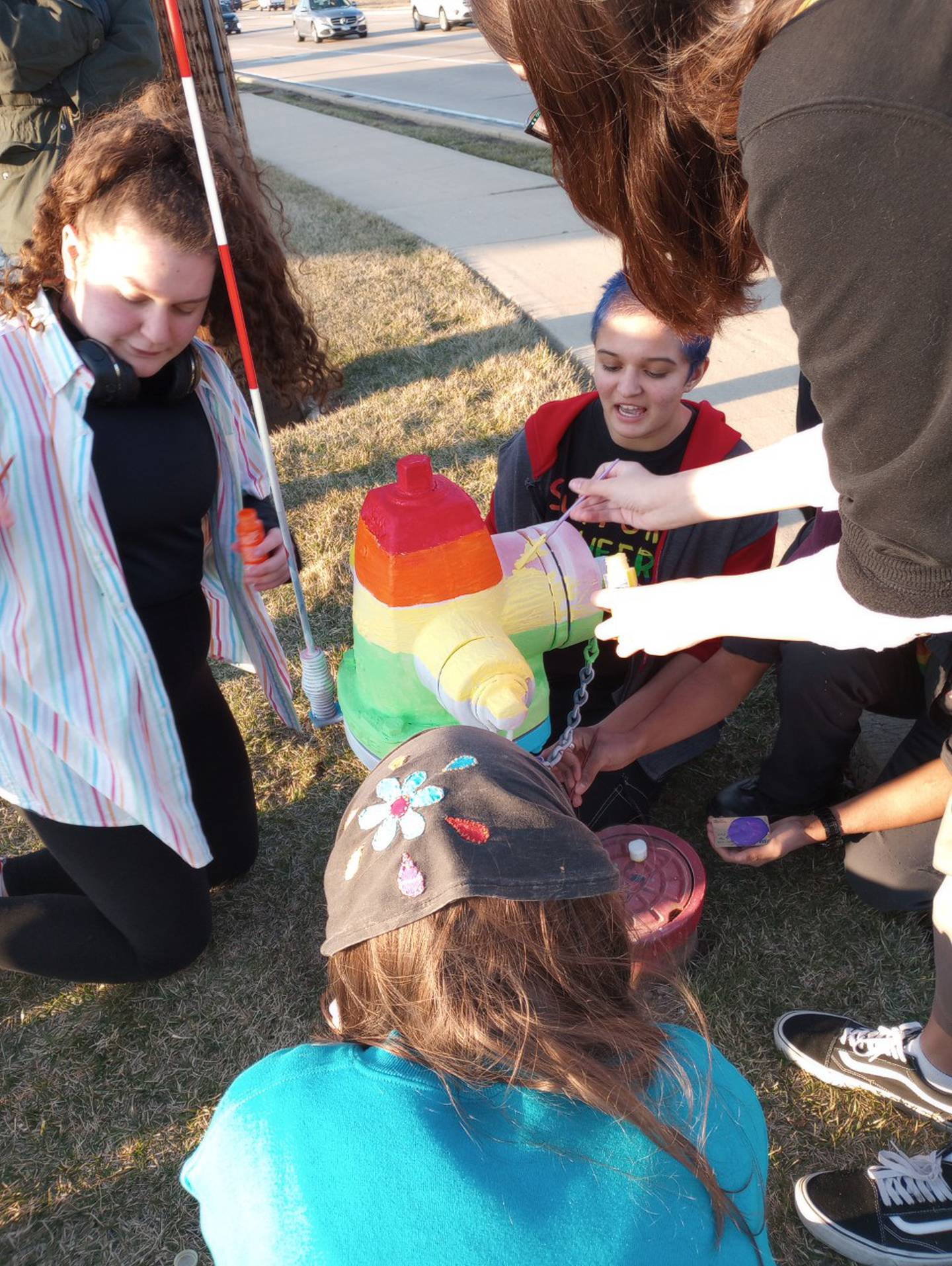 Geneva High School students Lily McConnell (left) Rani Foard, Kelly Jaros and Olivia Reich participate in repainting the rainbow Pride fire hydrant Tuesday after it was vandalized.