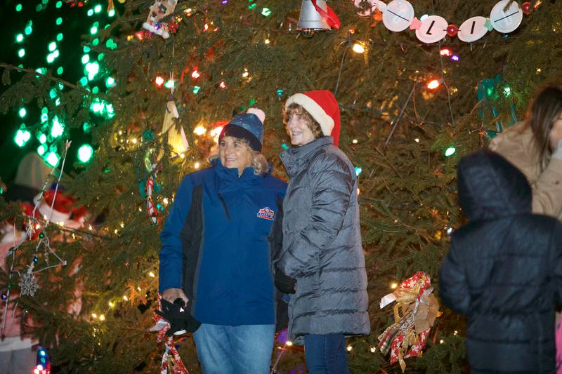 Christmas walk goers stop for a picture at the tree at the Geneva Christmas Walk on Friday, Dec.1 2023 in Geneva.