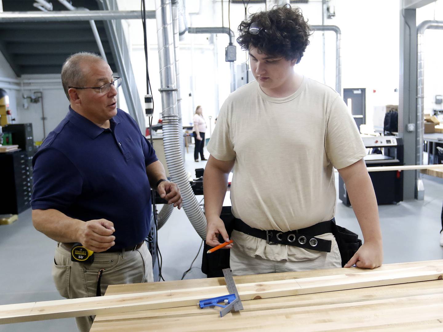 Teacher Dan Rohman talks with student David Mey as he teaches his construction trades students how to measure out a board to build a wall on Tuesday, Aug. 30, 2022, during class at McHenry High School. The students in the class will build the tiny shops that will house incubator retail businesses on McHenry's Riverwalk at Miller Point.