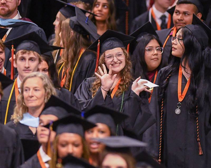 A St. Charles East graduate waves as she enters the commencement ceremony on Monday, May 18, 2026, held at the Convocation Center in DeKalb.