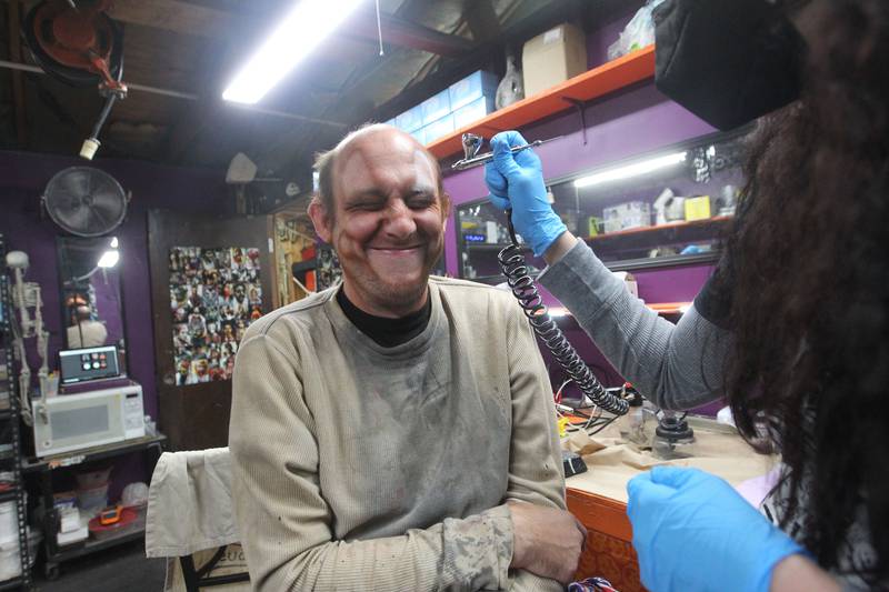 Nick Weber, of Mundelein gets his carny makeup put on by Liz Cannon, of Gurnee, makeup artist, as she uses an airbrush to apply it on his face at the Realm of Terror Haunted House in Round Lake Beach.