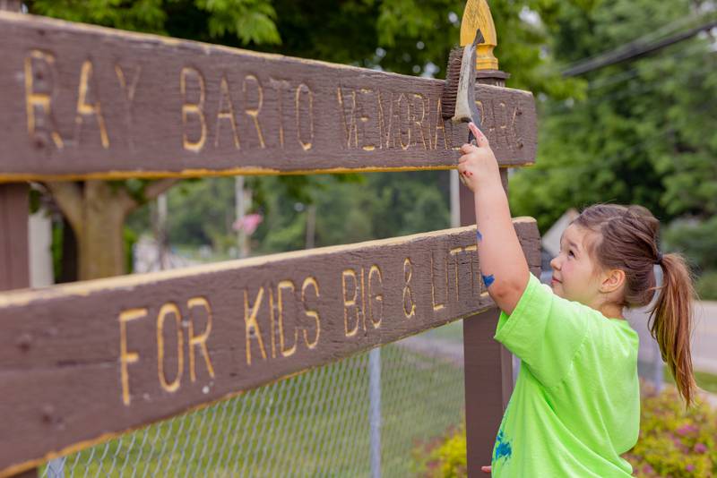 Everly Settlemeyer uses a wire brush to prepare a sign for painting at Ray Barto Memorial Park on June 3, 2025 in Seatonville.