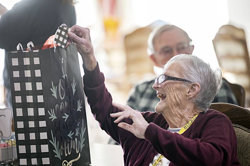 Dolores Gapen excitedly checks out a gift bag Wednesday, Dec. 13, 2023 at Heritage Woods in Sterling. Residents of the home were gifted the bags from Grace Point church.