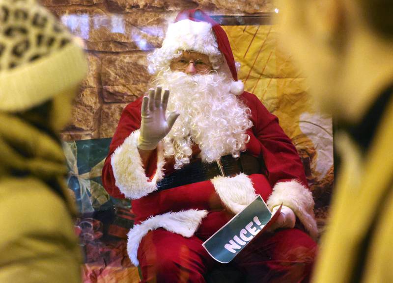 Santa waves at visitors passing by his window Friday, Nov. 21, 2025, during Moonlight Magic in downtown Sycamore.