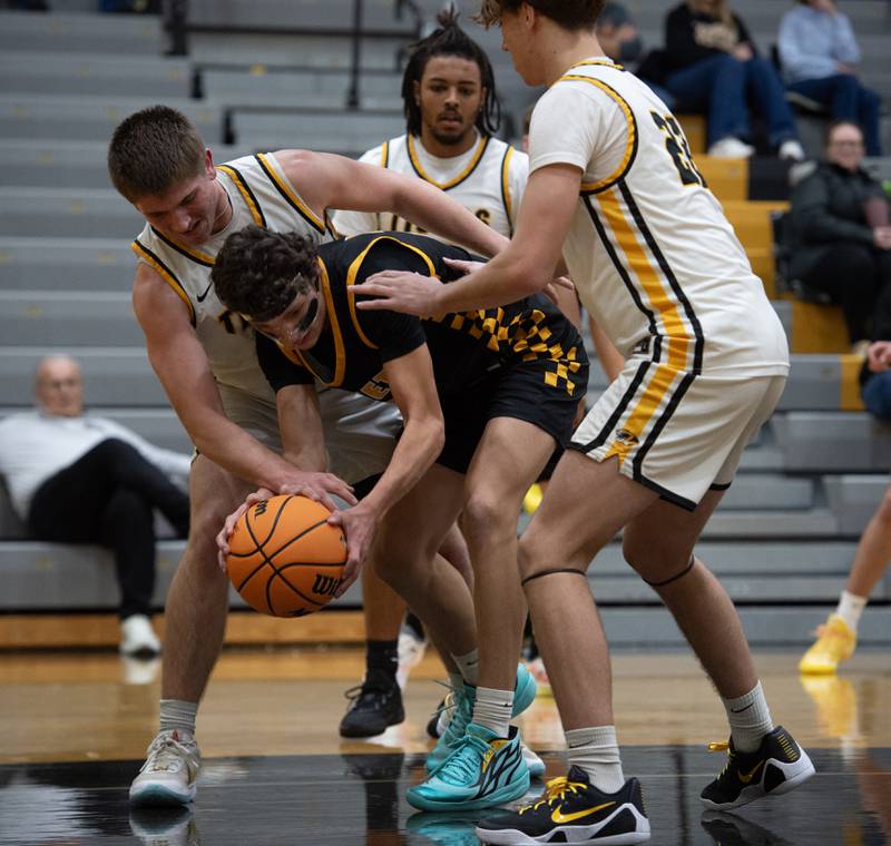 Herscher's Gavin Hull, left, and Tyler Lundberg, right, pressure Reed-Custer's Eddie Bryan, center, in a game on Wednesday, November 26, 2025.
