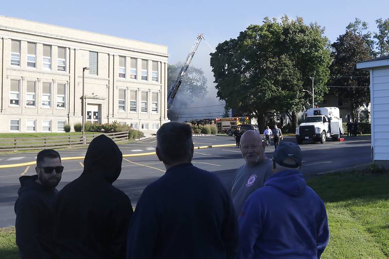 People watch as firefighters battle a house fire in the 300 block of Lincoln Avenue in Woodstock Monday, Oct. 9, 2023, after an explosion following suspected gas leak in the area.