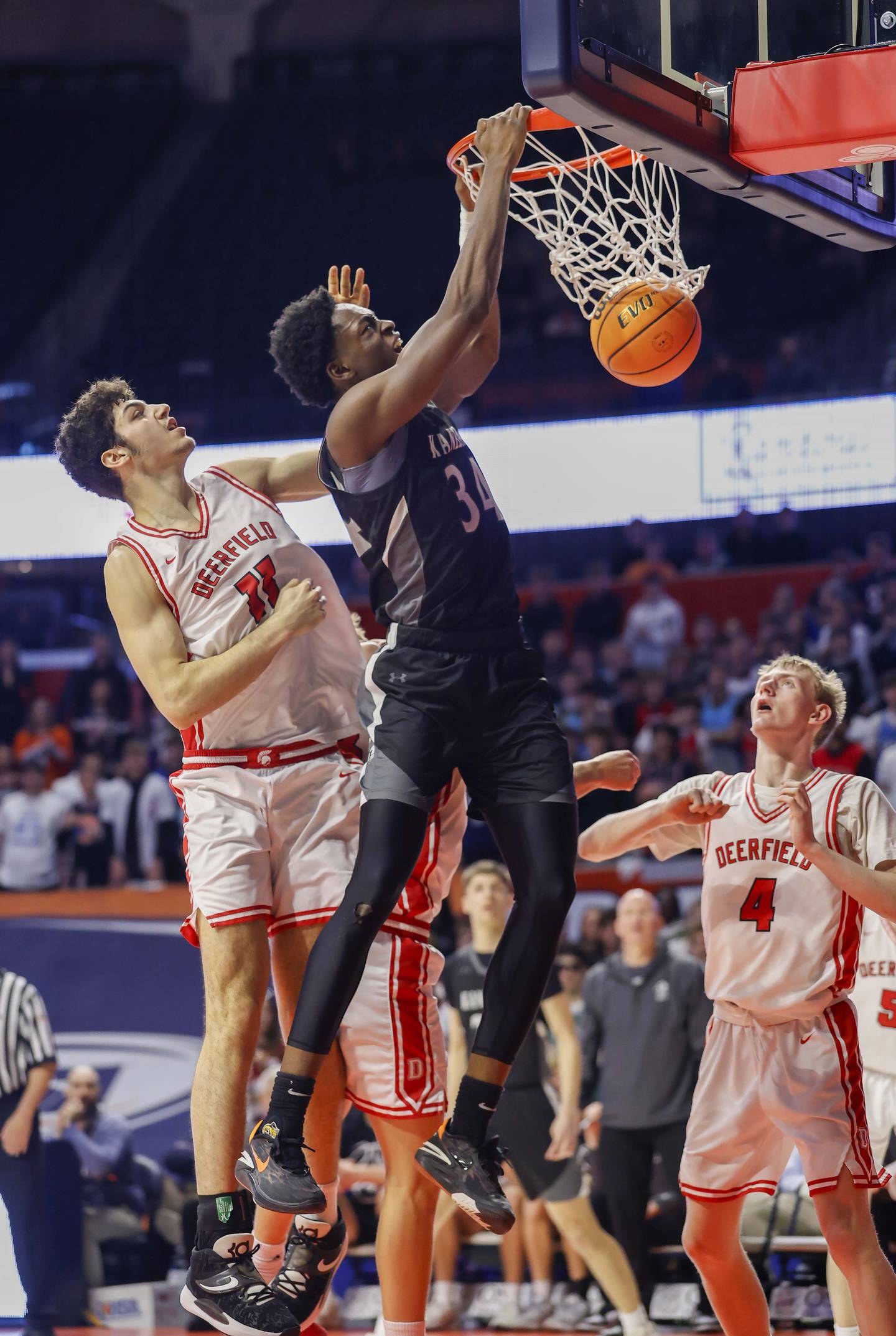 Kaneland's Jeffrey Hassan (34) throws down a dunk as Deerfield's Jake Pollack (11) attempts to block the shot during the IHSA Class 3A boys basketball state semifinal Friday, March 13, 2026 at the State Farm Center in Champaign.