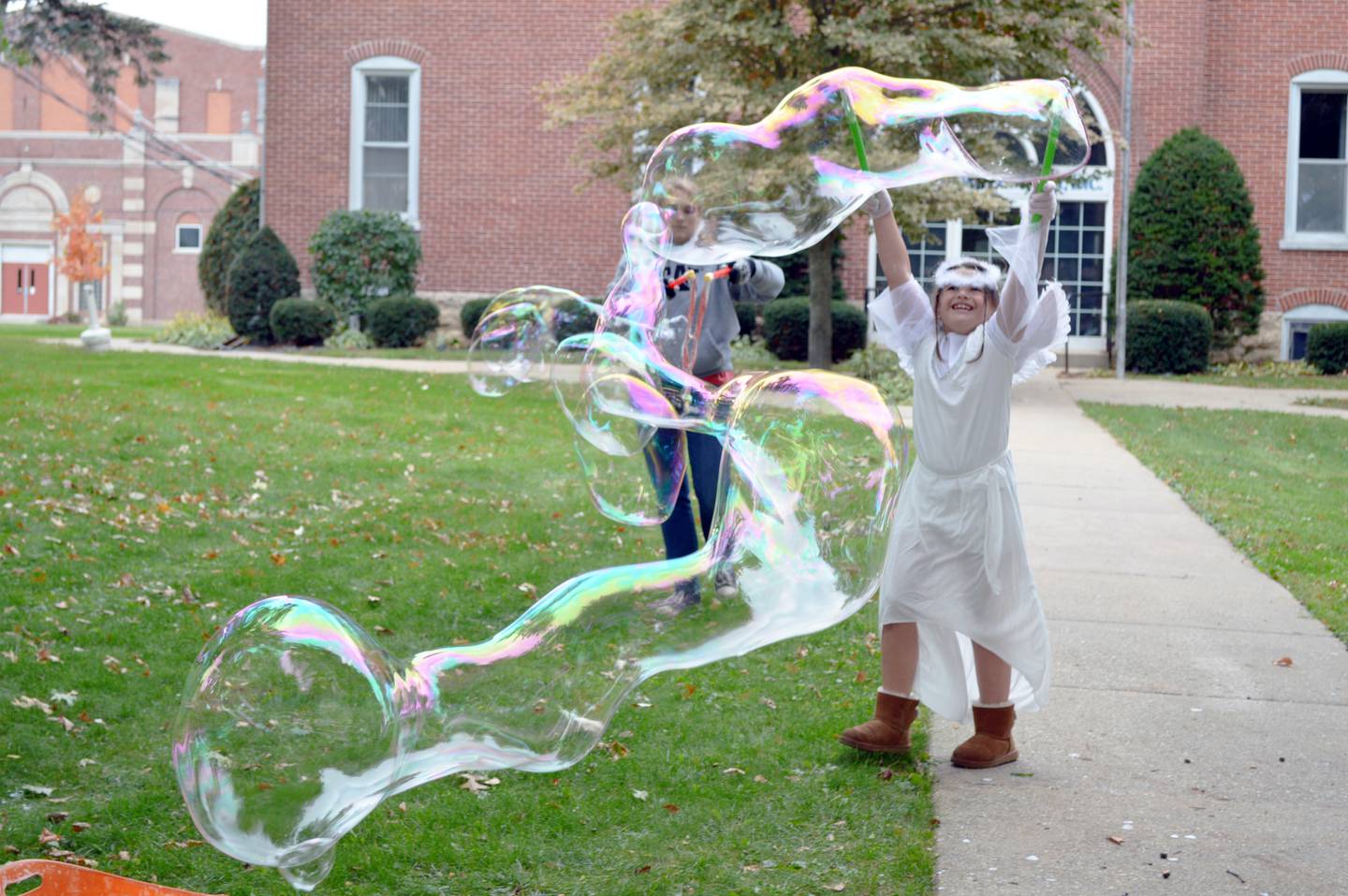 Adalynn Blumeyer, 7, of Oregon, grins as she creates massive bubbles during the Family Fall Festival at the Mt. Morris village square on Oct. 16. Adalynn's angel costume was one of many costumes worn to the event by attendees. This was the festival's first year; it serves as an additional fundraiser for the Let Freedom Ring Fourth of July fireworks.