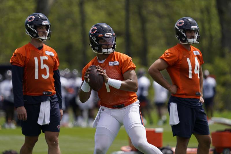 Chicago Bears quarterback Justin Fields throws a pass as Trevor Siemian, left, and Nathan Peterman look on May 17, 2022 during offseason practice at Halas Hall in Lake Forest.