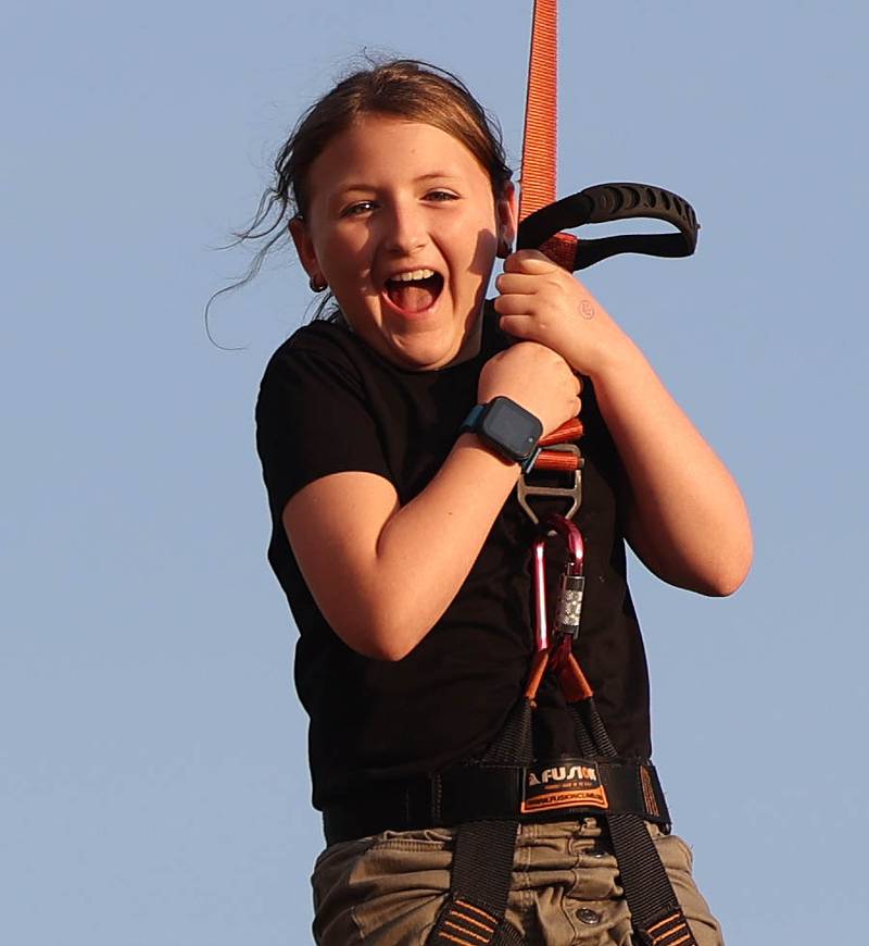 Vivian Grzywa, 8, from Sycamore, rides the zipline Thursday, Oct. 2, 2025, during the Huskie Homecoming Block Party in downtown DeKalb.