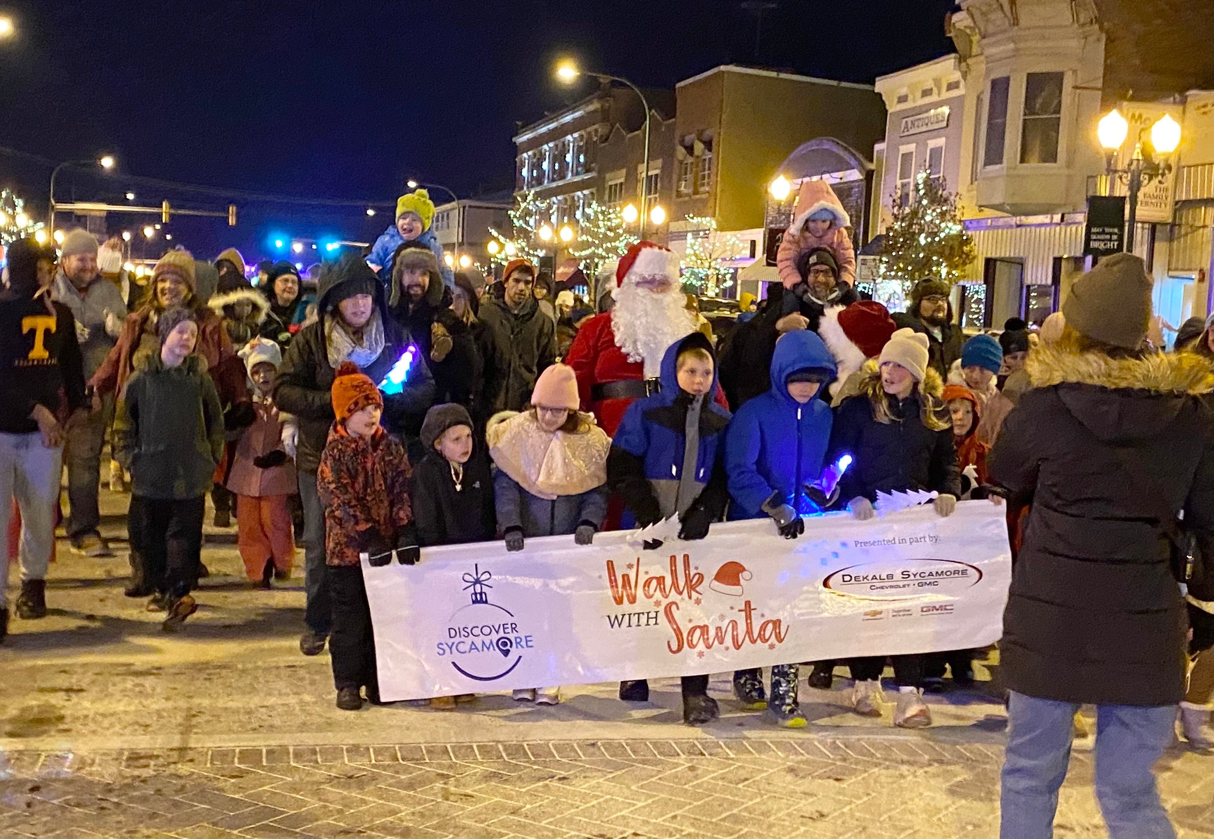 A crowd of children and their families walks with Santa Claus and Mrs. Claus on Friday, Dec. 5, 2025, in downtown Sycamore for the Sycamore Chamber of Commerce's annual Walk with Santa and lighting of the tree.