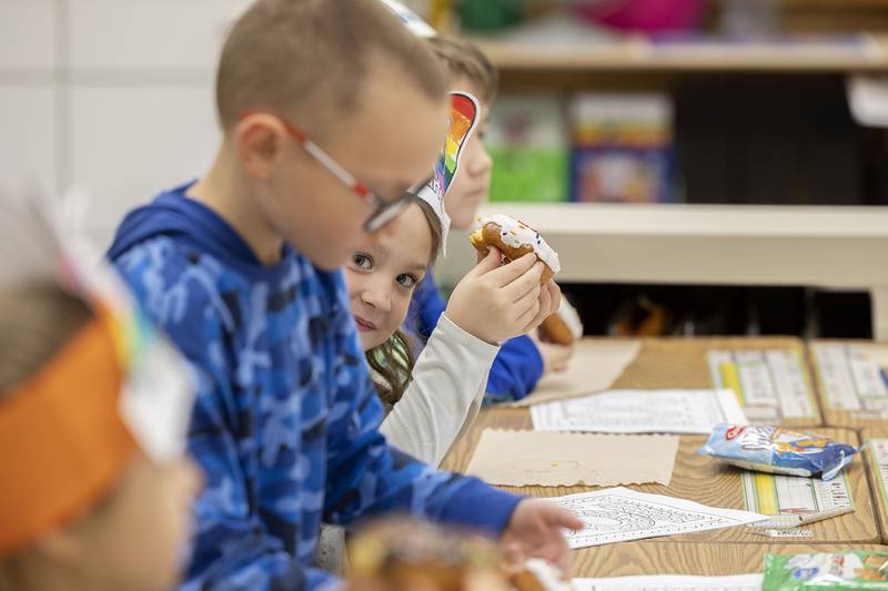 Shiloh Haas, peeks around while enjoying her doughnut in class at Jefferson School in Dixon. The kids could choose between a chocolate or vanilla frosted treat during the 100th day of class.