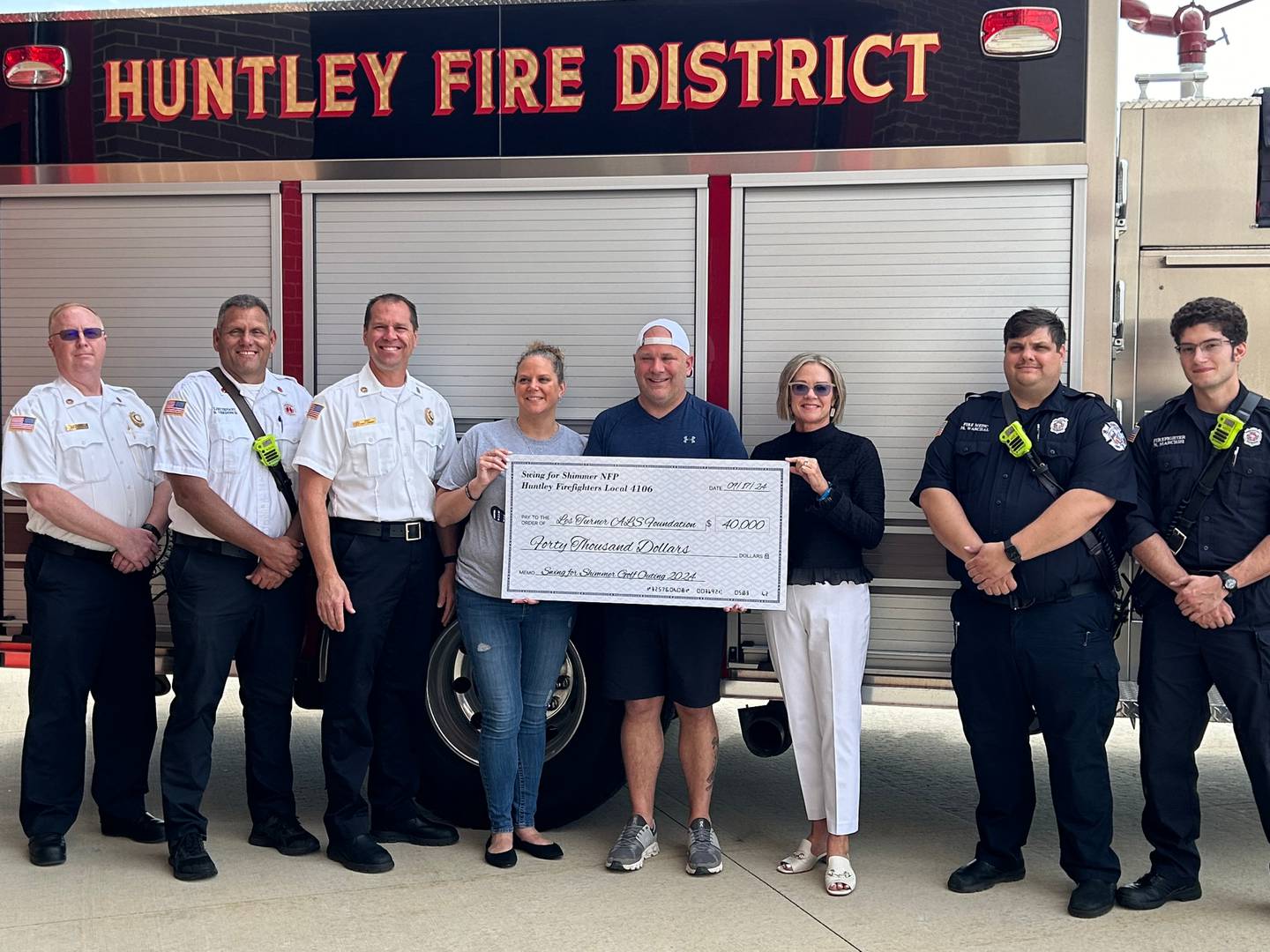 Jackie Szymczak, Bryan Szymczak and Laura Freveletti (from left to right in the center) stand with members of the Huntley Firefighters Local 4106, along with Fire Chief Scott Ravagnie and members staff of the Huntley Fire Protection District. The district donated $40,000 to the Les Turner ALS Foundation.