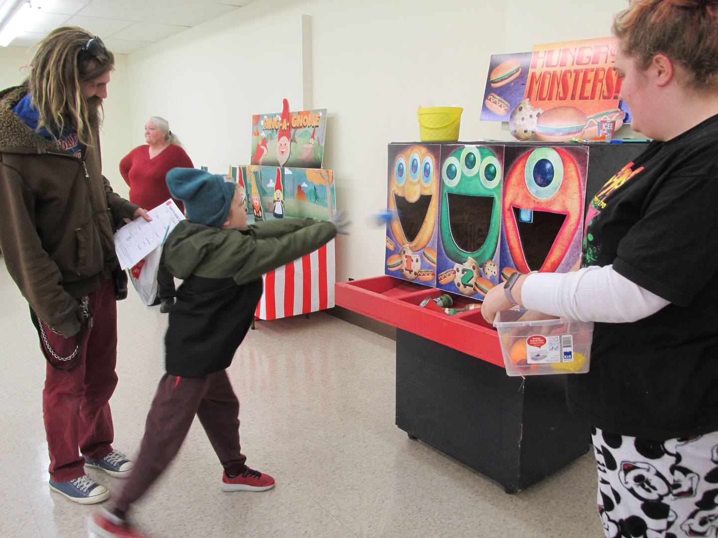 Will Drnach tries to throw a bean bag through one of the monster's mouths while playing a game Saturday, Nov. 12, 2022, during the Family Fun Fair at the Salvation Army in Ottawa.