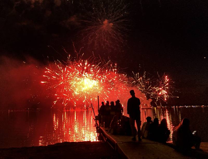 Young adults watch the fireworks show from a pier Sunday, July 2, 2023, at Crystal Lake’s Main Beach during Crystal Lake Annual Independence Day Celebration.