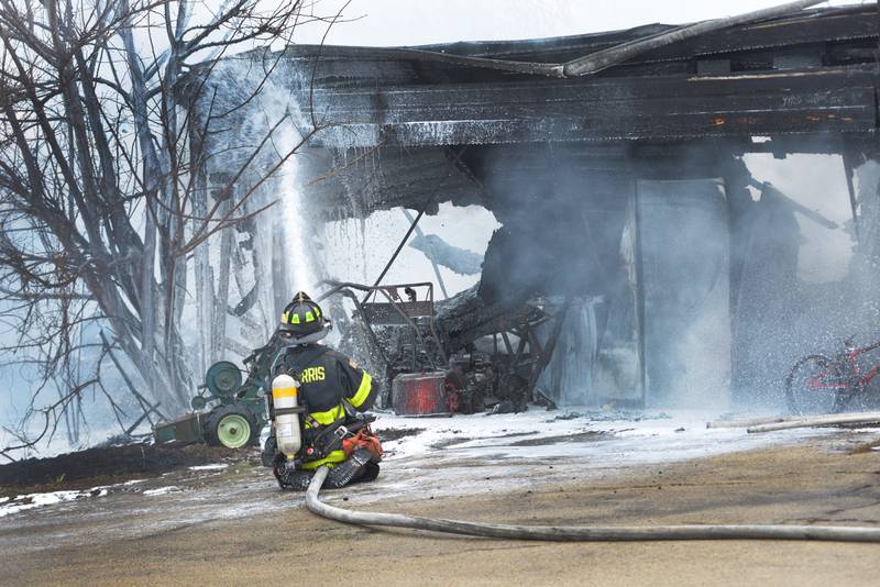 A Mt. Morris firefighter sprays down a garage at 6727 Henry Road, southeast of Polo, on Wednesday, March 26, 2025. Several departments responded to the fire at the rural residence.