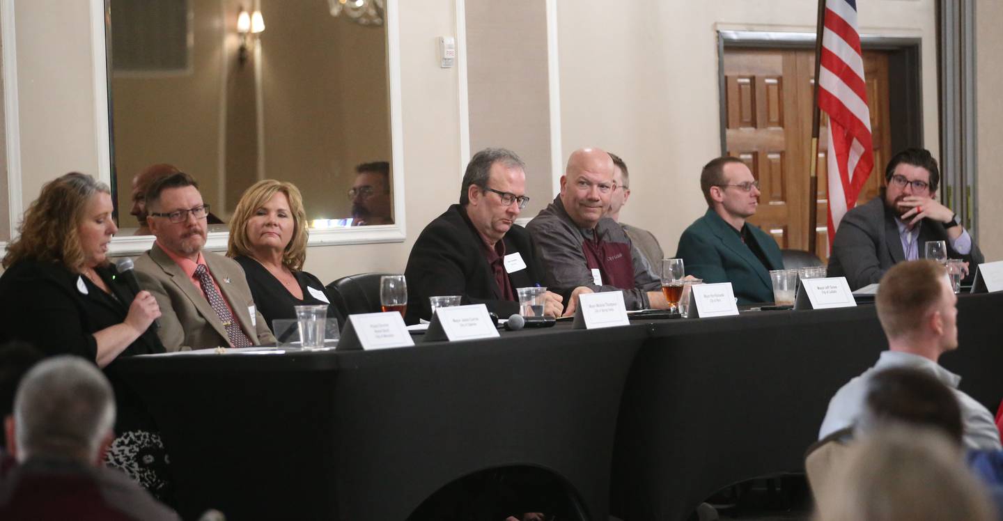 (From left) Annie Short speaks in the absence of Mendota mayor David Boelk, Oglesby mayor Jason Curran, Melanie Thompson, Peru mayor Ken Kolowski, La Salle mayor Jeff Grove, Ottawa mayor Rob Hasty, Utica mayor Dave Stewart and Illinois Valley Chamber of Commerce executive director Bill Zens, gather during the Illinois Valley Chamber of Commerce "State of the Cities" luncheon on Wednesday, March 26, 2025 at Grand Bear Lodge in Utica.