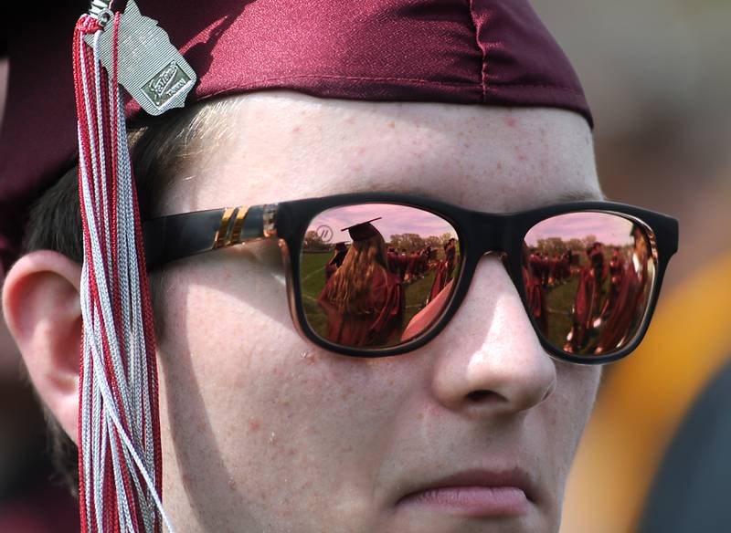 A classmate is reflected in Mitchell Hopkins’s sunglasses Saturday, May 14, 2022, during the graduation ceremony at Prairie Ridge High School.