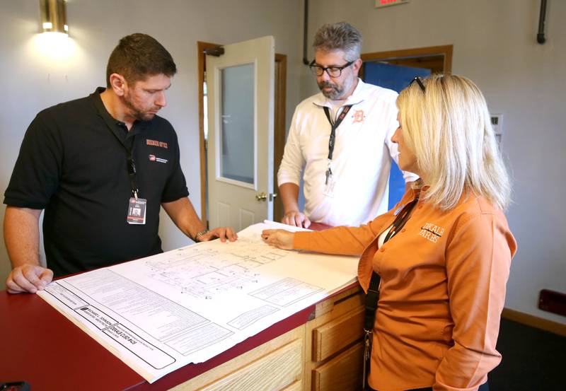 Tammy Carson, (right) director of facility operation services for DeKalb School District 428, talks about the blue prints for the new transition program facility Friday, Aug. 9, 2024, with business and finance director Armir Doka, (left) and Ben Bayle, chief technology officer, during the Beyond One Barb Transition Center Construction Kick-Off event at the new site at 530 Charter St. in DeKalb.