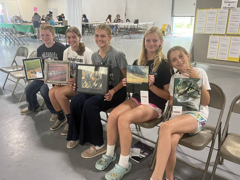 A group of 4-H members hold up photography projects in Smith 4-H Hall as they await conference judging.